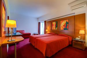 a hotel room with a red bed and a couch at Hotel Alvorada in Estoril