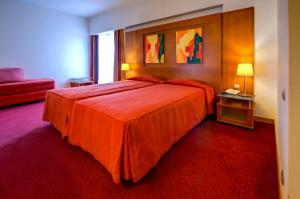 a bedroom with a large red bed and a red carpet at Hotel Alvorada in Estoril
