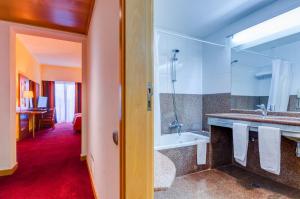 a bathroom with a tub and a sink and a shower at Hotel Alvorada in Estoril