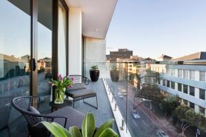 a balcony with chairs and tables and a view of a city at Botanik Apartment Hotel in Sydney