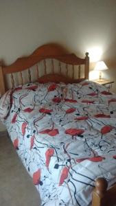 Una cama con una manta con flores rojas. en Lo de Charly en Sierra de la Ventana