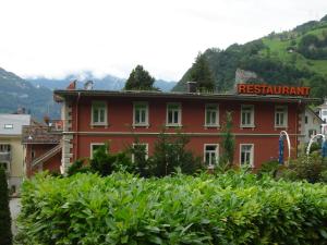 um edifício vermelho com um sinal de restaurante vermelho em Hotel Eden Sisikon em Sisikon