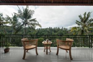 2 Stühle und ein Tisch auf einem Balkon mit Aussicht in der Unterkunft Villa Tepi in Ubud