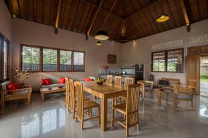 a dining room and living room with a table and chairs at Villa Tepi in Ubud