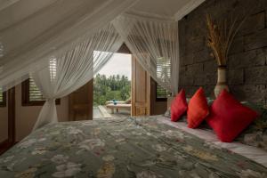 a bedroom with a large bed with red pillows at Villa Tepi in Ubud