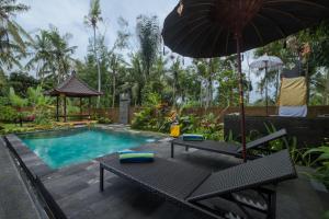 - une piscine avec une table, un parasol et un banc dans l'établissement Puri Astina Villa, à Ubud