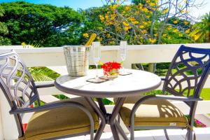 einen Tisch und zwei Stühle auf einem Balkon mit Weingläsern in der Unterkunft One Hamilton Place - Emerald in Choiseul