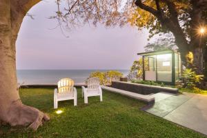 two chairs sitting in the grass near the ocean at Baan Sandao by Nanni in Hua Hin