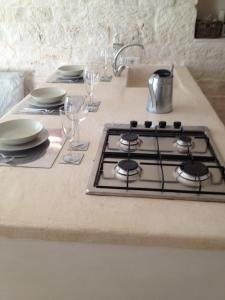 a kitchen counter with a stove and plates and glasses at Il Granello Di Senape In Valle D'Itria in Locorotondo