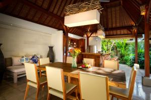 a dining room with a wooden table and chairs at Villa Vastu Seminyak in Seminyak