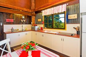 una cucina con armadi bianchi e un tavolo con fiori di Possum Lodge At Cloudhill Estate a Mount Tamborine