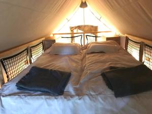 a bed in a tent with two pillows on it at Anfasteröd Gårdsvik - Tälten in Ljungskile