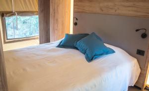 uma cama com um travesseiro azul em cima em Anfasteröd Gårdsvik - Tälten em Ljungskile