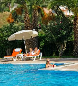 two people sitting in a swimming pool next to a woman at City's Hill Hotel in Kuşadası