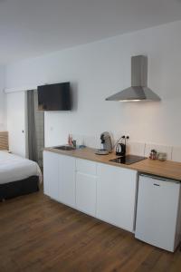 una cocina con armarios blancos y una cama en una habitación en Appart Albert'House en Clermont-Ferrand