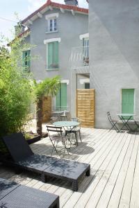 um pátio com uma mesa e cadeiras num deque de madeira em Appart Albert'House em Clermont-Ferrand