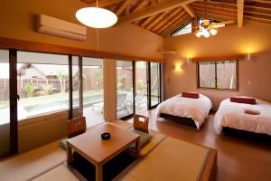 a bedroom with two beds and a table and a room with at Onsensui Pool & Fufu Rotenburo no Hanareyado Yurian in Ibusuki