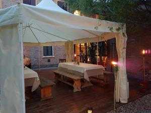 a white tent with a table and benches under it at Corte Dossello in Migliaro