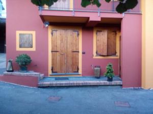 梅萊的住宿－B&b Al Ciliegio Del Turchino，粉红色的房子,有木门和两盆植物