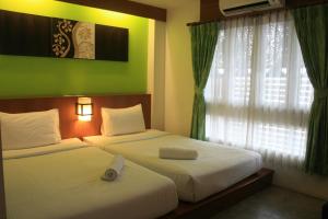 deux lits dans une chambre d'hôtel avec une fenêtre dans l'établissement Baan Ing Ping, à Chiang Mai