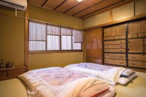 a bedroom with two beds and cabinets and windows at Kyo Yukari in Kyoto