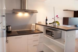 uma cozinha com armários brancos e um balcão com um micro-ondas em Résidence Le Mas de Valrugues (by Popinns) em Saint-Rémy-de-Provence