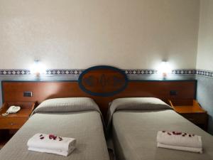 Dos camas en una habitación de hotel con toallas blancas. en Hotel Kroma, en Ragusa