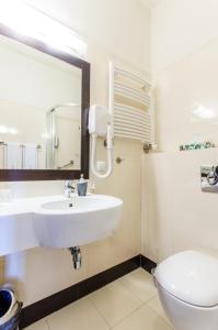 een badkamer met een wastafel, een toilet en een spiegel bij Locomotiva in Lublin