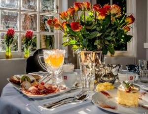 una mesa con platos de comida y un jarrón de flores en The Villa Rosa Guest House & Self-catering Apartments, en Ciudad del Cabo