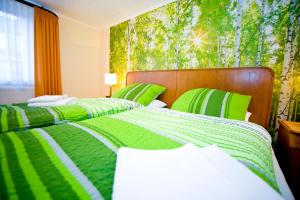 ボーデンヴェルダーにあるKorbmacherhausの緑と白のシーツが備わる客室のベッド2台