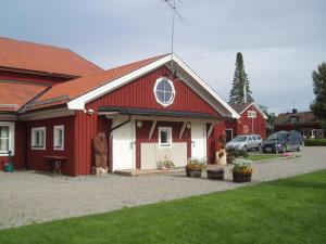 Un fienile rosso e bianco con una statua davanti. di Åbyggeby Landsbygdscenter a Ockelbo