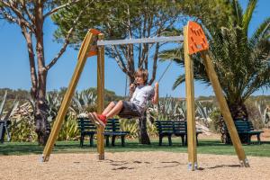 a young girl sitting on a swing at a park at NAU Salema Beach Village in Salema