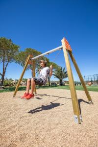 a man sitting on a swing in a park at NAU Salema Beach Village in Salema