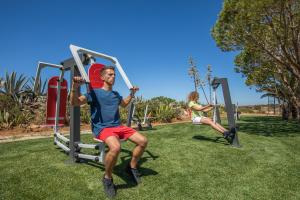 a man sitting on a swing in a park at NAU Salema Beach Village in Salema