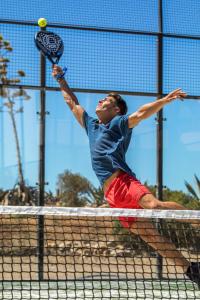 a man hitting a tennis ball with a racket at NAU Salema Beach Village in Salema