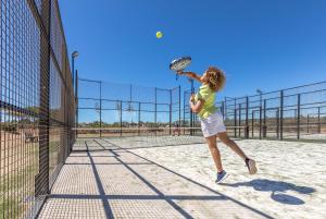 a woman swinging a tennis racket on a tennis court at NAU Salema Beach Village in Salema