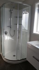 a shower with a glass door in a bathroom at Woodbury Farm B&B in Takanini