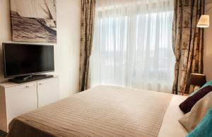 Schlafzimmer mit einem Bett, einem TV und einem Fenster in der Unterkunft Apartment Bruno Summerland in Mamaia