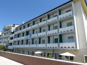 un edificio de apartamentos con balcones blancos y sombrillas en Hotel Stella Maris, en Grado