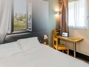 Schlafzimmer mit einem Bett, einem Schreibtisch und einem Fenster in der Unterkunft B&B HOTEL Bordeaux Lormont in Lormont