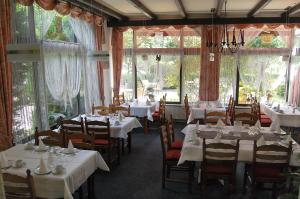 een eetkamer met witte tafels, stoelen en ramen bij HANSA Hotel in Mendig