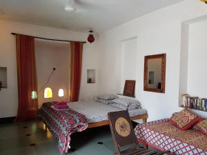 a bedroom with two beds and a chair and a mirror at Silver Moon Haveli in Udaipur