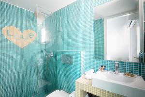 uma casa de banho com paredes em azulejos azuis, um lavatório e um espelho. em Acqua Vatos Paros Hotel em Parikia