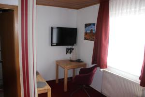 une pièce avec une télévision, une table et une chaise dans l'établissement Hotel und Restaurant Hohenzollern, à Erfurt