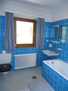baño de azulejos azules con bañera y lavamanos en Josefinenhof, en Neustift im Stubaital