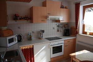 a kitchen with a stove and a microwave at Ferienwohnung Burger in Sasbach am Kaiserstuhl