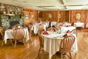 um restaurante com mesas e cadeiras brancas e uma lareira em The Vermont Inn em Mendon