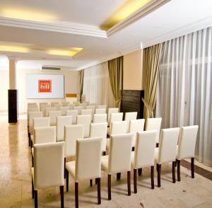 a conference room with white chairs and a screen at City's Hill Hotel in Kuşadası
