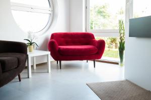 a red chair in a living room with a window at City Rooms Szczecin in Szczecin