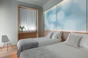 a bedroom with two beds and a chair and a window at Air Suite Verona in Verona